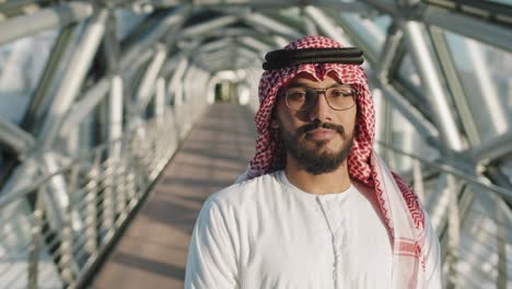 portrait of young sheikh standing at glass bridge