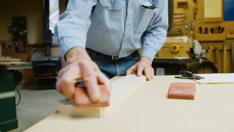 woodworker sands a piece of wood in his workshop