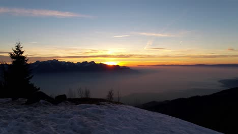 Toma-Aérea-De-La-Puesta-De-Sol-Sobre-El-Mar-De-Niebla,-Alpes-Suizos-En-El-Paisaje-Nevado-De-Fondo