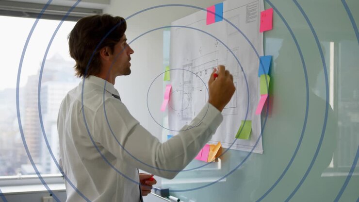 Facing plan, man adjusting pink sticky note, marking glass with red marker for business planning