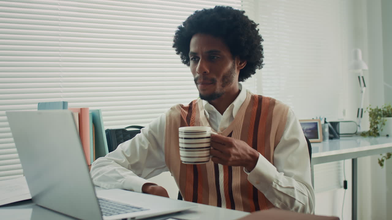 Businessman Drinking Tea while Greeting Colleagues Meeting Online on Video