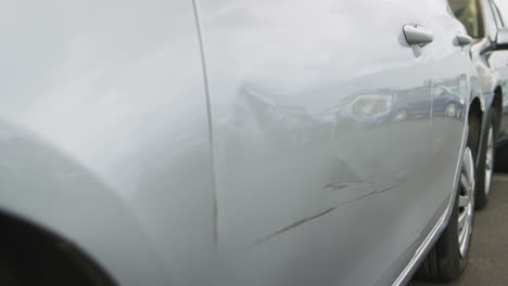 detail of car with door panel damaged in motor vehicle accident parked in garage repair shop