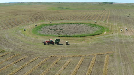 antenna di un trattore che scarica una balla di fieno secco, scenario di terreni agricoli in giornata di sole