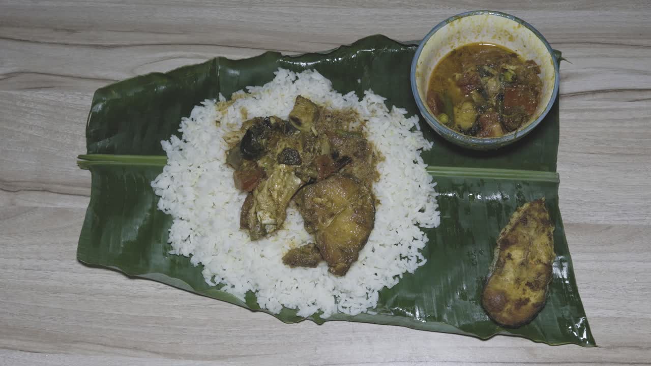 girl eating fresh and hot fish and rice cooked meal served at banana leaf for dinner