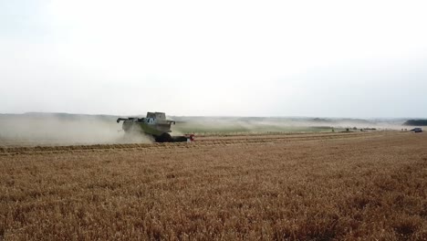 Eine-Filmische-4K-Drohnenaufnahme-Eines-Mähdreschers-Bei-Der-Ernte-Eines-Feldes-In-Frankreich,-Die-Die-Landwirtschaft-Mit-Epischer-Aussicht-Und-Dramatischem-Staub-Zeigt