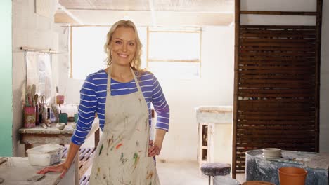 beautiful female potter standing in pottery shop