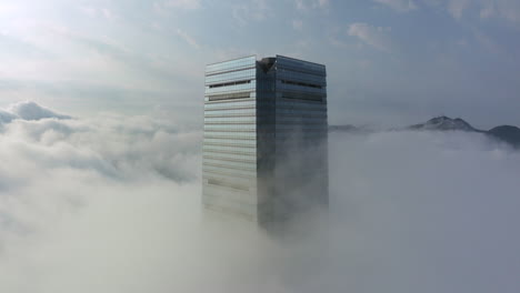 panning shot of icc skyscraper in hong kong with bright sunlight in low morning clouds