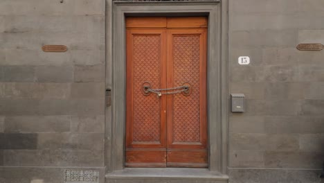 establishing, static shot of ornate wooden door in rome, chained and padlocked through ornate door knockers