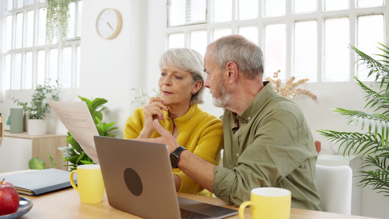 Casal sênior analisando documentos e usando um laptop juntos em casa