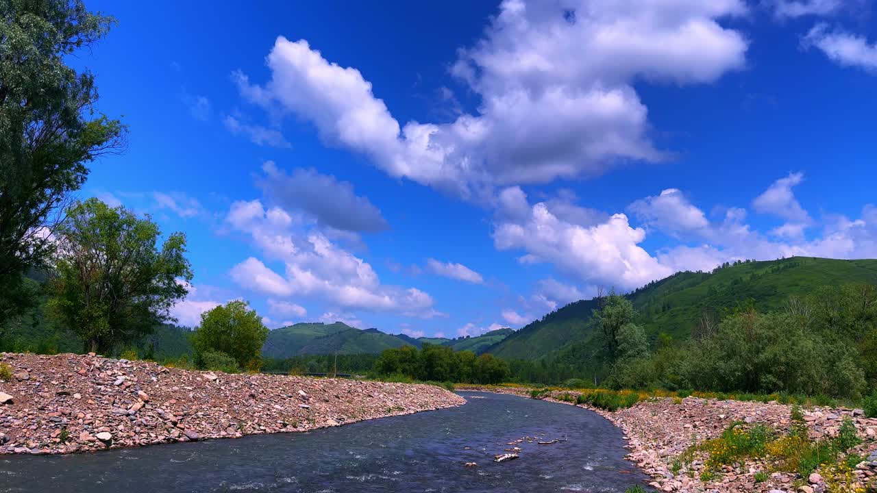 A Serene Landscape: Captivating Views of a Tranquil River Curving Through Lush Green Hills Under a Bright Blue Sky with Fluffy Clouds