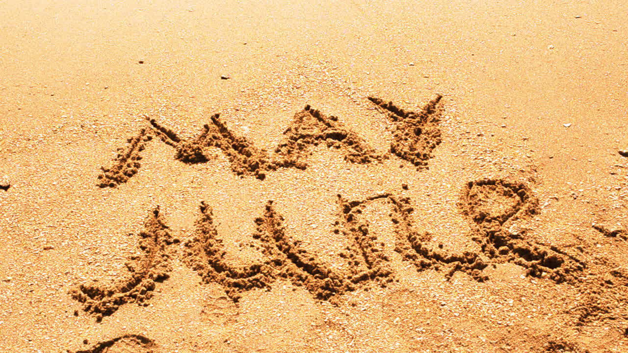 Iscrizione del nome del mese sulla sabbia, la spiaggia. Scatto sulla spiaggia.