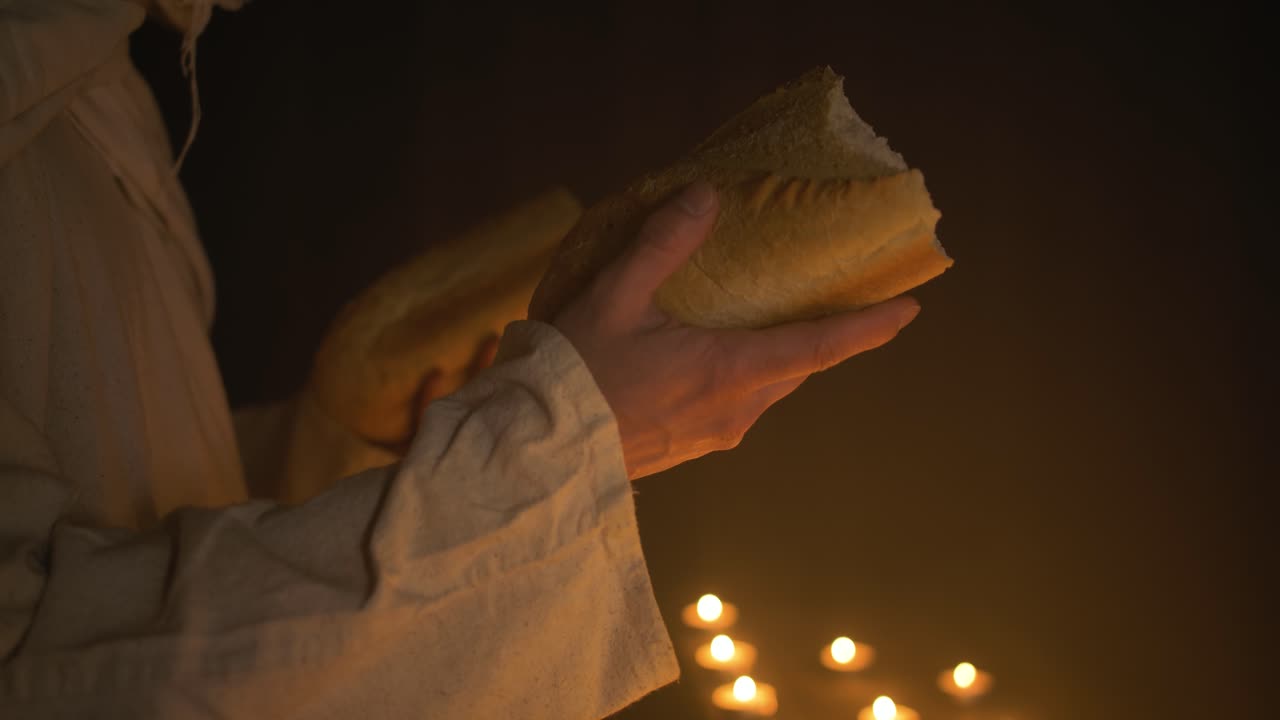 Jesus Christ holding bread for Passover, communion, sacraments, last supper over candlelight for Christianity stock footage