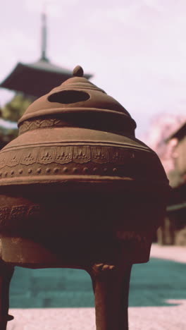 close up of a traditional incense burner in front of a japanese pagoda