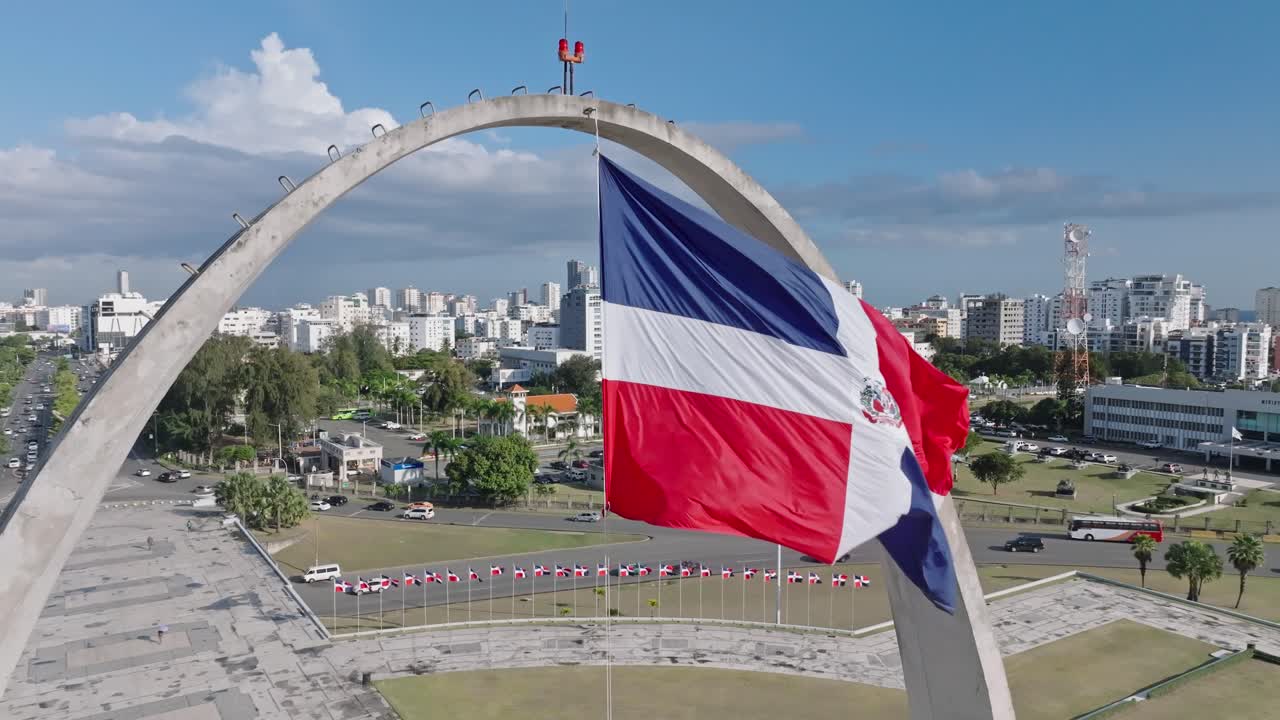 bandeira nacional da república dominicana balançando com o vento na praça da bandeira de santo domingo, república dominicana - aérea, câmera lenta