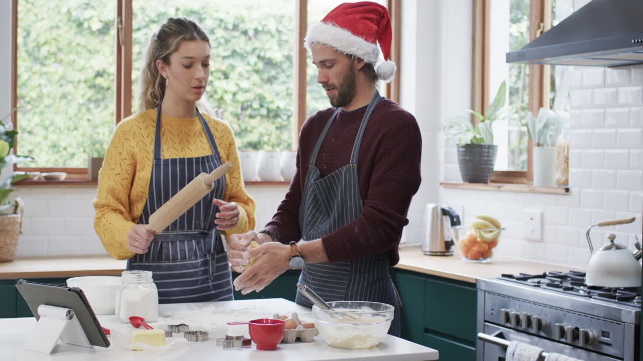 una pareja feliz horneando galletas de navidad en la cocina de casa, en cámara lenta.