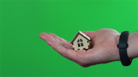 close up footage of male hand holding little house over chroma key background