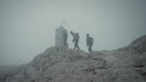 hikers arriving at the peak of mountain triglav in front of aljaž tower