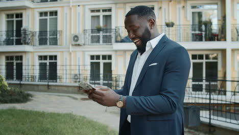 cheerful businessman counting money outdoors