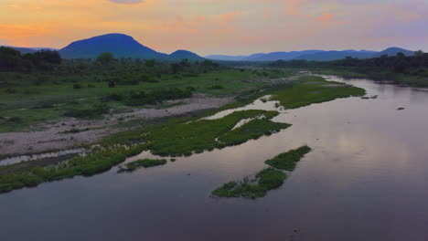 drone entrada kruger parque nacional cinematográfico naranja rosa rojo puesta de sol en el río puerta sur pájaros flamenco cocodrilo debajo lluviosa primavera verde exuberante impresionante paisaje montañoso movimiento hacia adelante