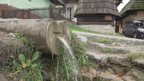 pequeña cascada de madera artificial en el campo rodeada de casas tradicionales en el pueblo tradicional vlkolinec, eslovaquia