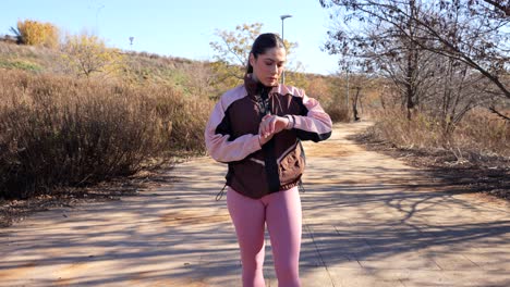 mujer revisa su reloj inteligente durante una carrera al aire libre soleada en un camino tranquilo