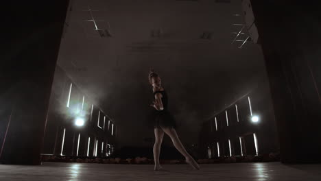 a slowly dancing ballerina in front of spot lights. several spotlights show a dancing ballerina at a dark stage in slow motion