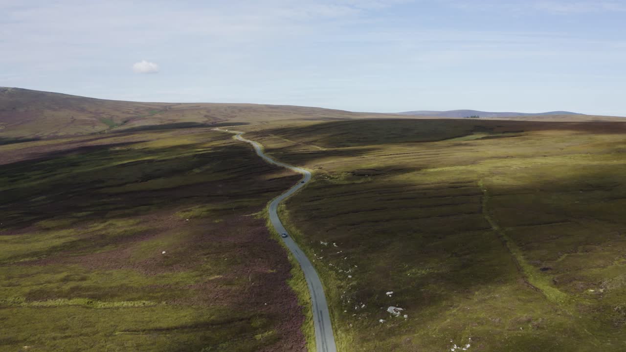 vista aérea de los coches que circulan por una larga y sinuosa carretera de montaña en las montañas de wicklow en un día soleado