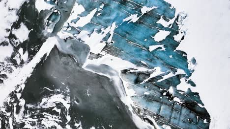 aerial view over colorful, powder snowy glacier ice in iceland - top down, drone shot