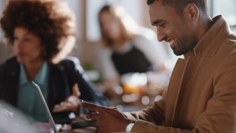 Junger-Geschäftsmann-Benutzt-Laptop-Im-Café-Und-Blättert-Nachrichten-Auf-Dem-Smartphone,-Trinkt-Kaffee-Und-Arbeitet-Online-In-Einem-Belebten-Restaurant