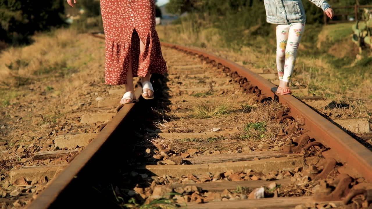 기찻길에서 놀고 있는 엄마는 딸에게 균형을 잡는 방법을 보여줍니다.