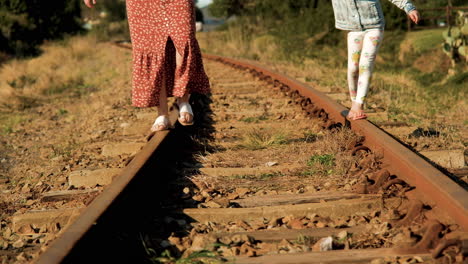 Playing-on-the-railway-tracks,-mom-shows-daughter-how-to-balance