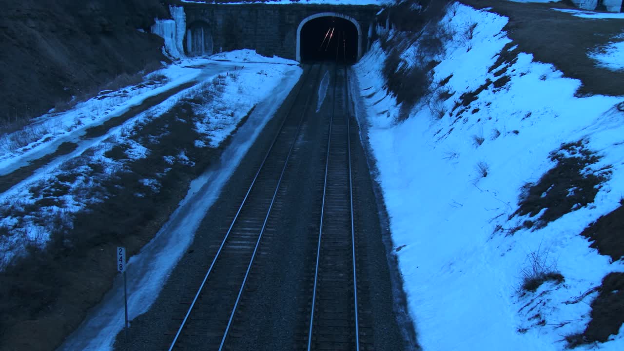 ángulo alto sobre un tren de carga que atraviesa un túnel por la noche en invierno