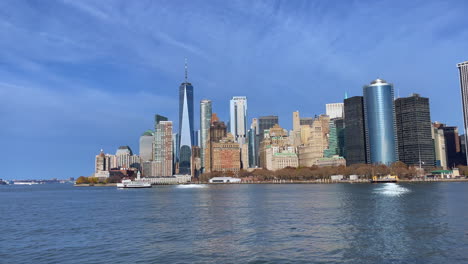 high skyline of new york city on a sunny day as a ferry sails across and a large bird flies around