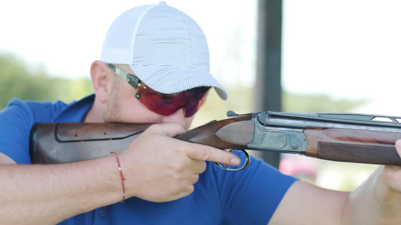 스포츠맨이 이중 배럴 건으로 총을 고, 슈팅 테스트를 위한 스포츠 경기장은 날아다니는 스케이트를 고 있습니다.