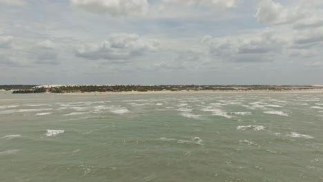 Lange-Drohnenaufnahme-Vom-Meer-Zum-Strand,-Vorbei-An-Kitesurfern-In-Brasilien