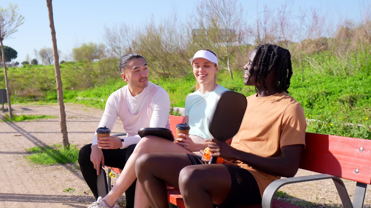 Diverse Friends Socializing and High-Fiving on a Park Bench After Pickleball