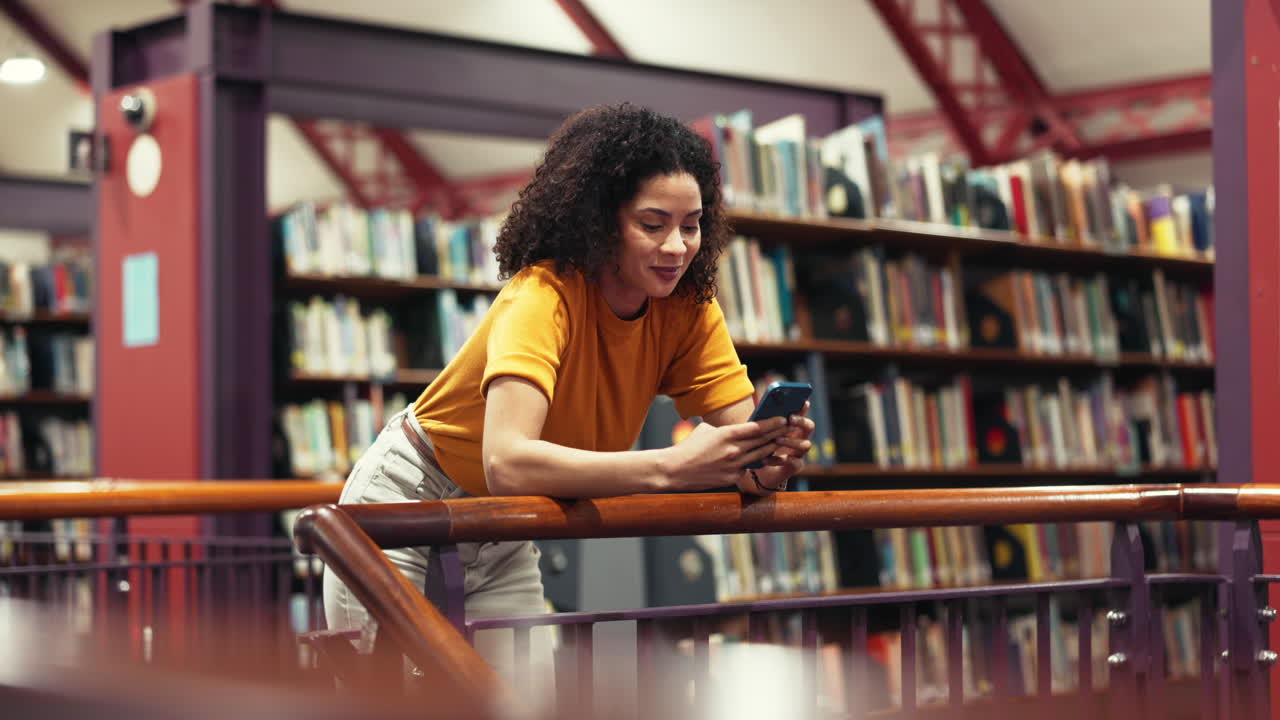 Frau, die in der Bibliothek ein Handy benutzt