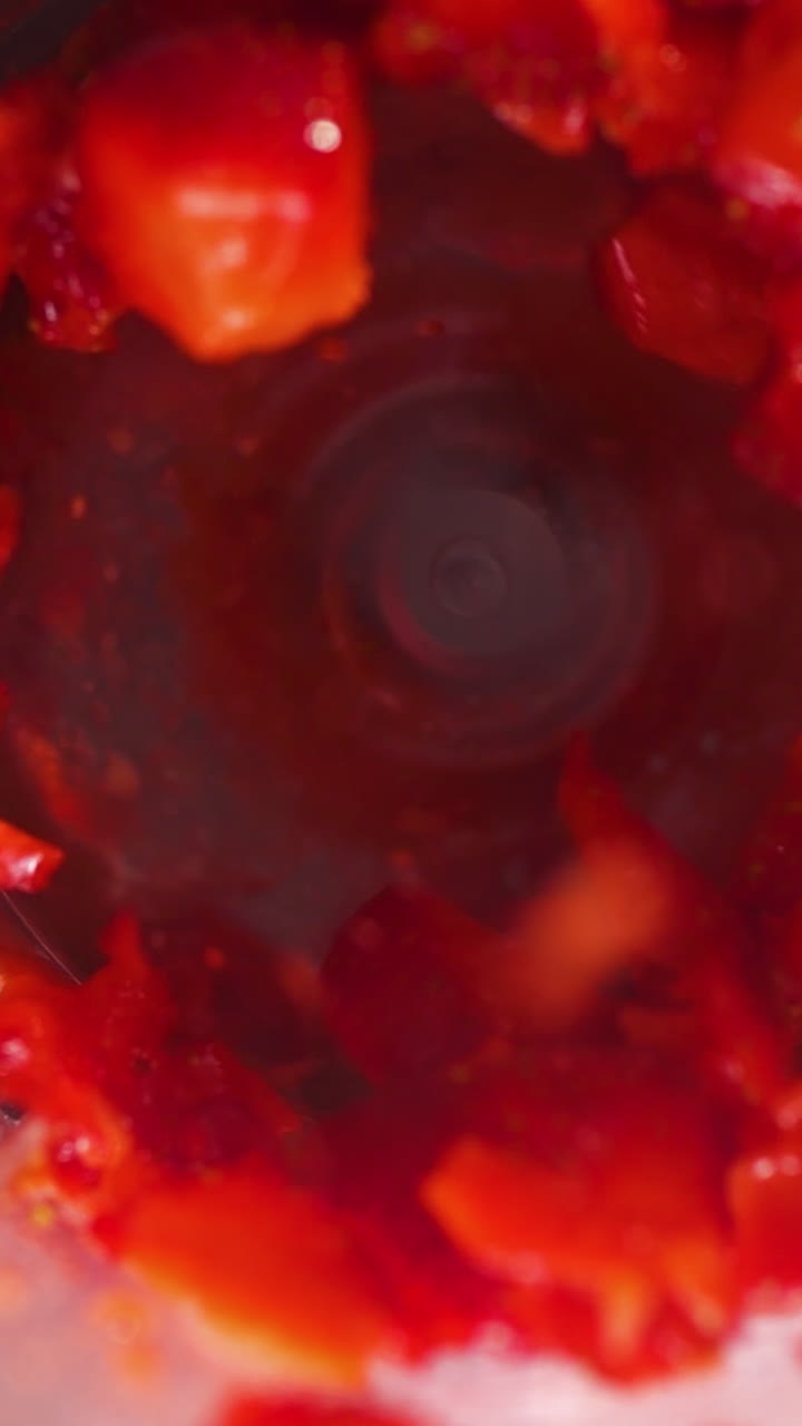 A close-up slow-motion shot of vibrant strawberries dropping into a spinning mixer, highlighting blending fresh ingredients and movement. ideal for organic food, smoothie, or recipe content.