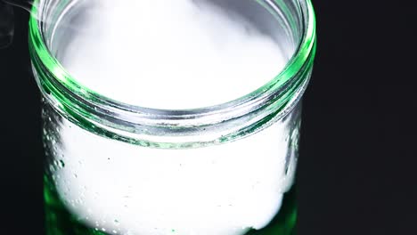 un vaso con hielo seco crea vapor nebuloso, mostrando una reacción química en un entorno controlado