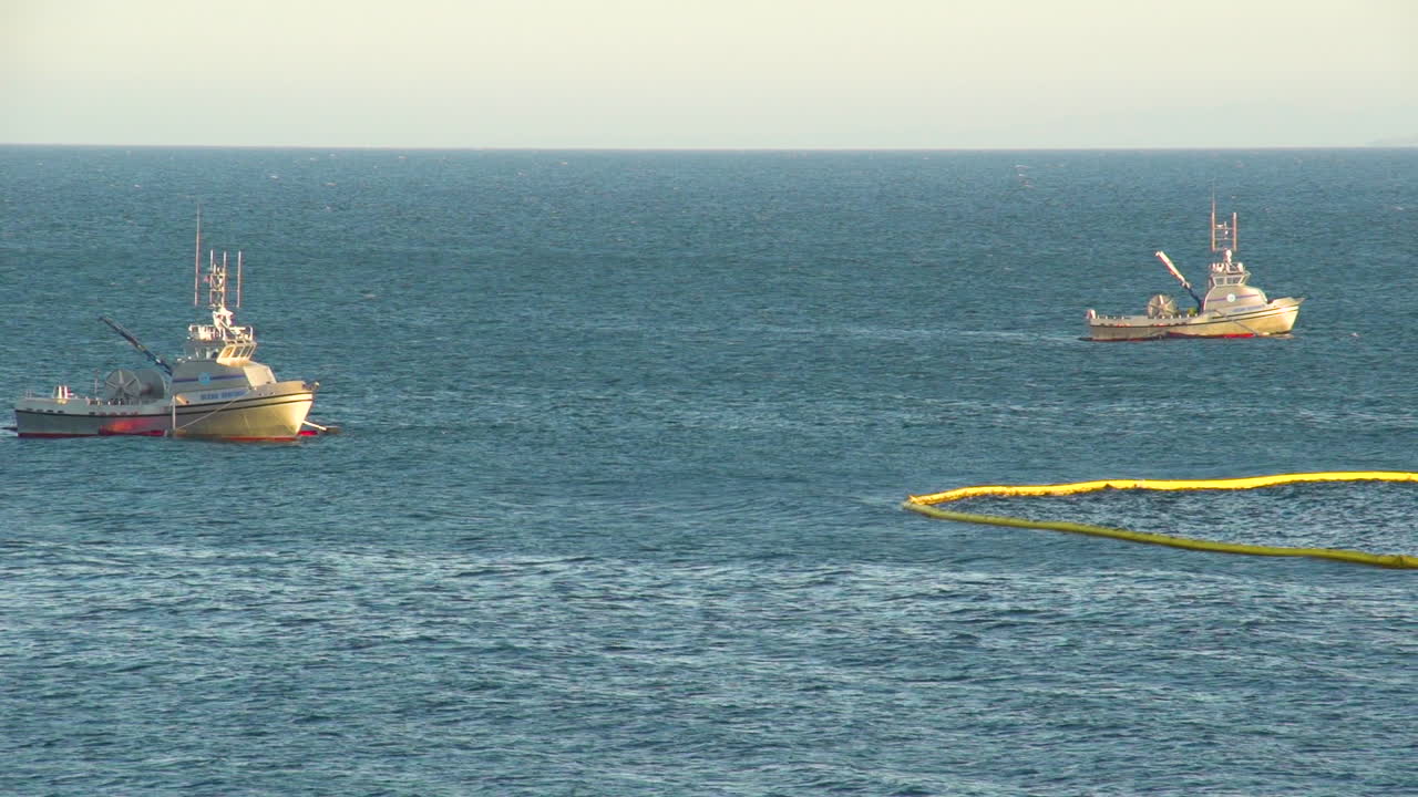 레퓨지오 기름 유출 1 이후 대규모 해변 청소 작업 후 보호망을 설치하는 비상 보트