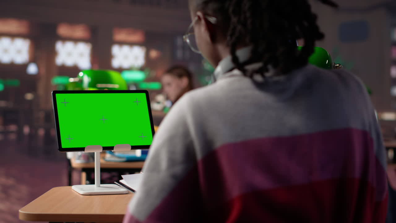 Vertical video college student looks at isolated chroma key screen at the campus library