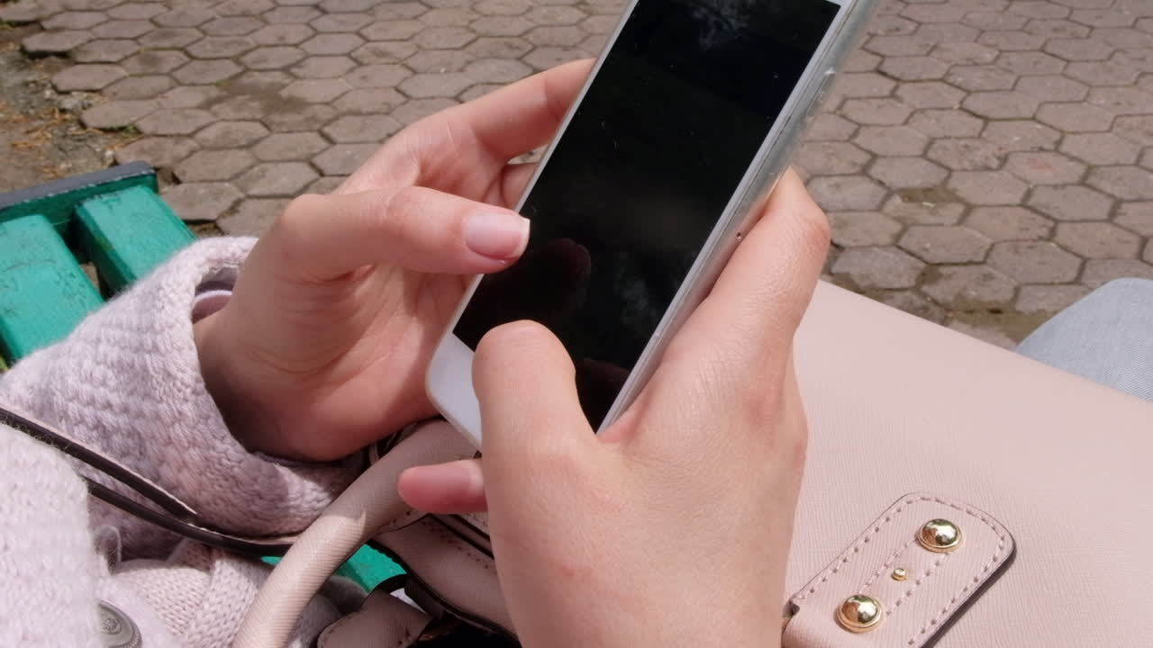 Close up of a a woman scrolling through her phone in a park