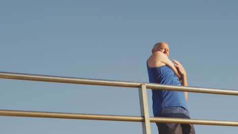 Senior-man-stretching-his-arms-on-the-promenade