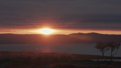 midnight sun passes on the horizon, casting a warm light over the landscape