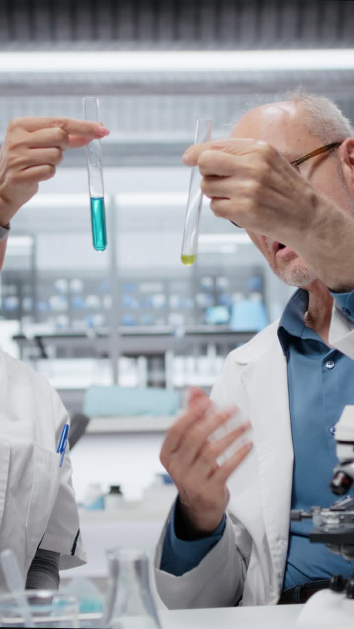 Seniorforsker underviser praktikant i laboratoriet for at evaluere sammensatte opløsninger i et lodret format.