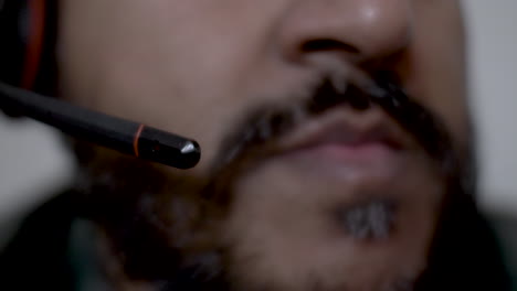 primer plano del micrófono boom de los auriculares bajando con un fondo borroso de un hombre barbudo de minoría étnica hablando