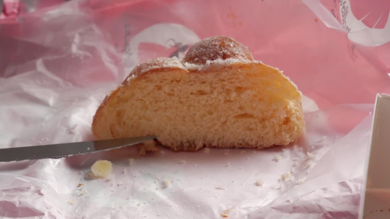 Female and male hand picking slice of Bread of the Dead, "Pan de Muerto". Traditional spiced sweet bread from Mexico served on All Saint's Day celebration.