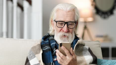 close up portrait of old man wearing glasses, sittiing and video chatting on cellphone