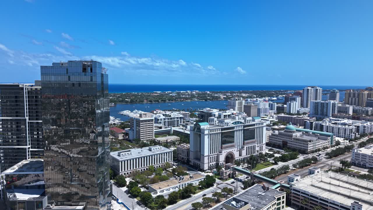 Aerial: downtown West Palm Beach cityscape with Atlantic Ocean during the day in Florida, USA, push in drone shot
