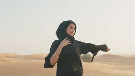 retrato de una mujer musulmana con hiyab sonriendo a la cámara en un desierto ventoso 1